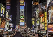 New York Times square at night, brightly lit and busy.