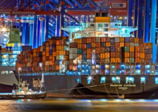 A tugboat pulls a large cargo ship into port