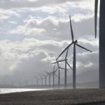 A line of wind turbines along a cost