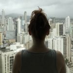 Woman looking at city outside window
