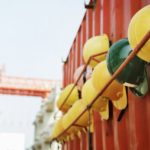 a row of hard helmets hanging from the wall of metal container