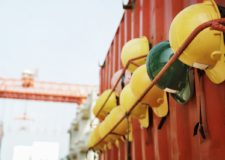 a row of hard helmets hanging from the wall of metal container