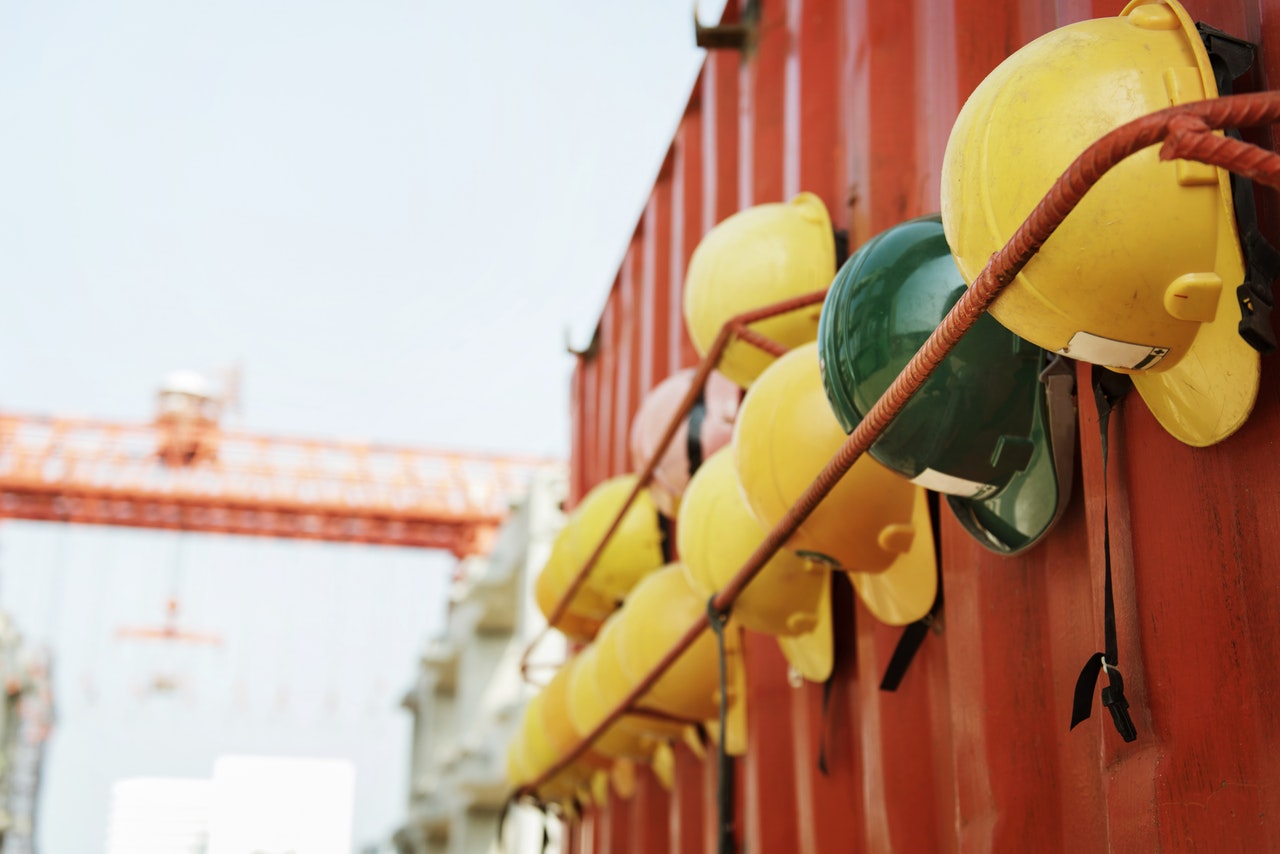 a row of hard helmets hanging from the wall of metal container
