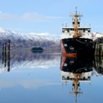 A ship docked in front of a snow capped mountain