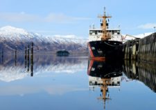 A ship docked in front of a snow capped mountain