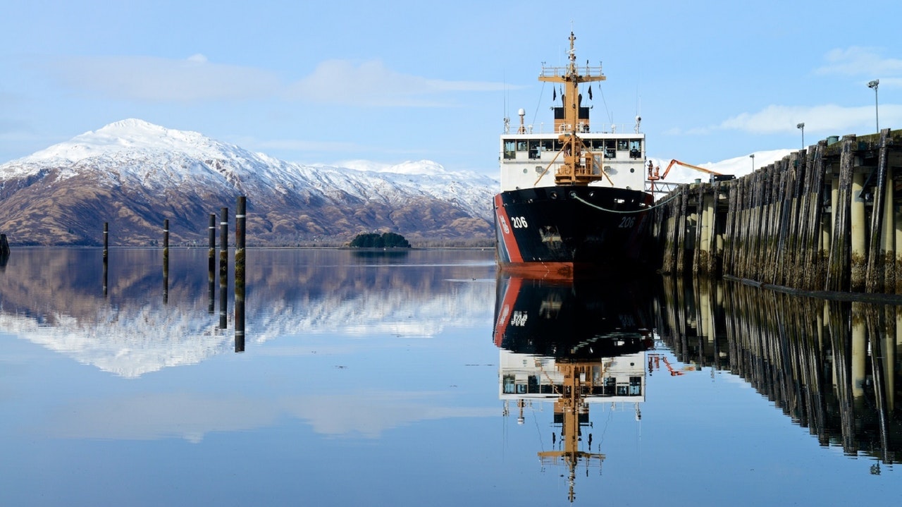 A ship docked in front of a snow capped mountain