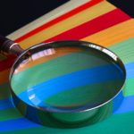 A magnifying glass placed on top of colourful papers