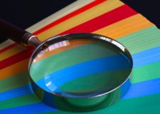 A magnifying glass placed on top of colourful papers