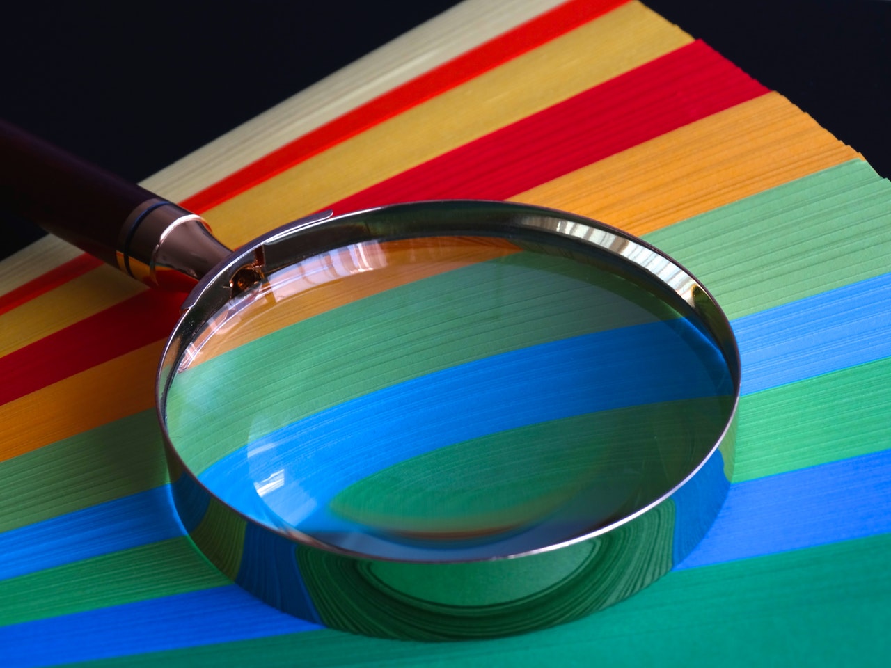 A magnifying glass placed on top of colourful papers