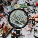 Magnifying glass spotting dollar bills amid a mess of objects
