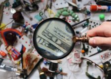 Magnifying glass spotting dollar bills amid a mess of objects