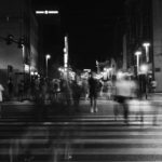 Black and white photo of a blurred people crossing a road