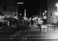 Black and white photo of a blurred people crossing a road