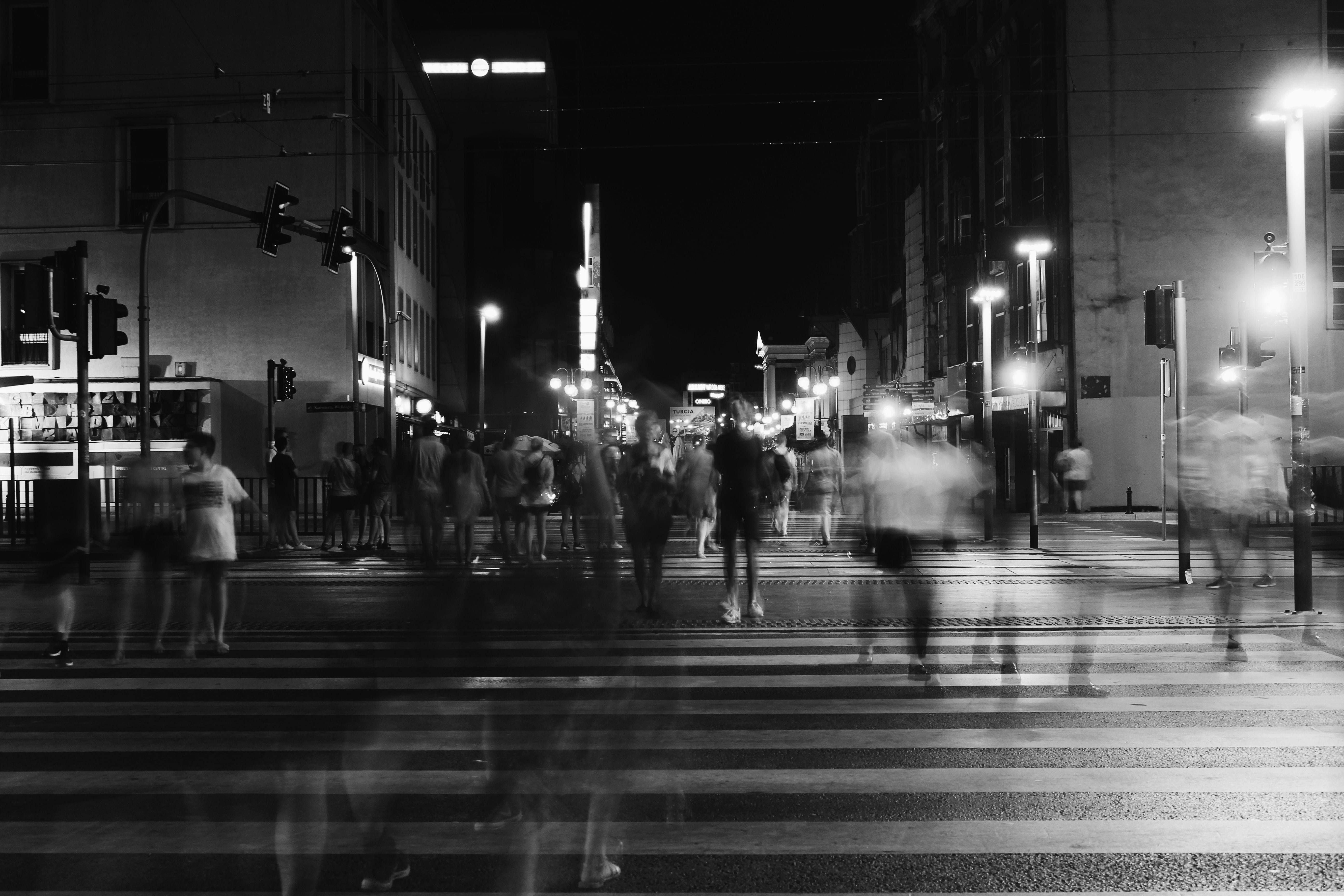 Black and white photo of a blurred people crossing a road
