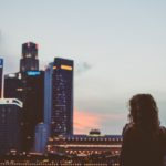 Woman stands facing financial district skyscrapers