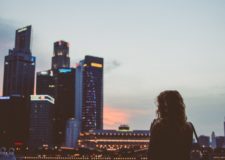 Woman stands facing financial district skyscrapers