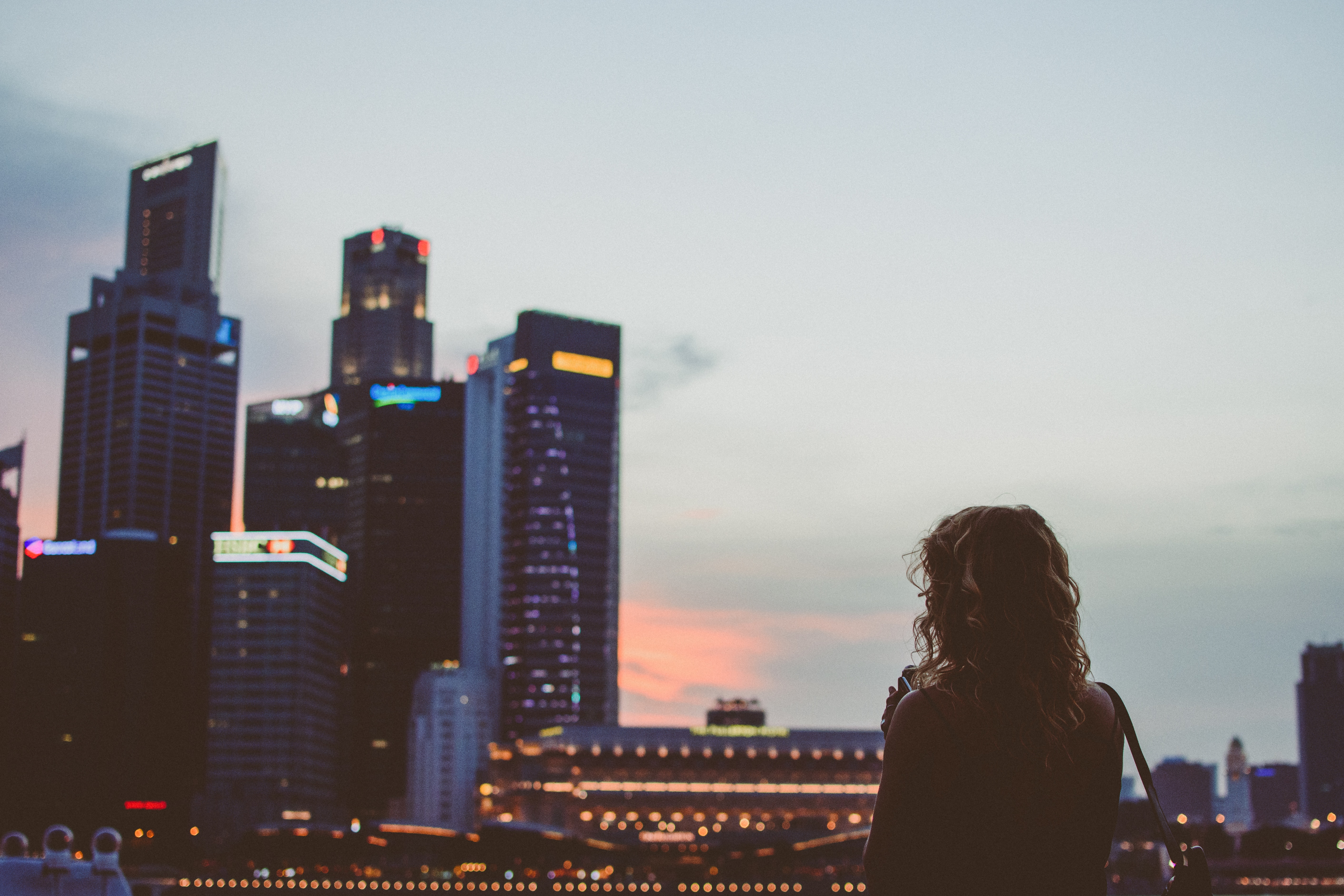 Woman stands facing financial district skyscrapers