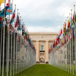 Two rows of national flags outside of a UN building